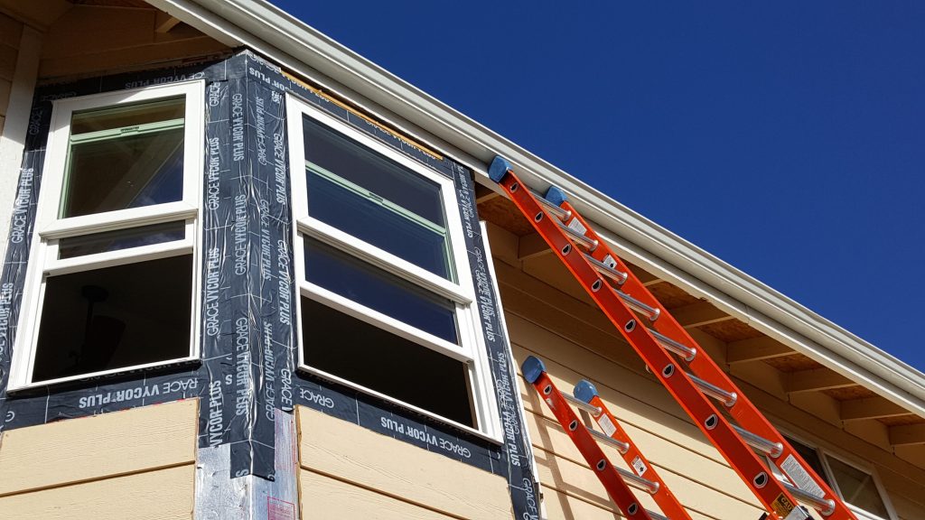 Window being installed on tan house