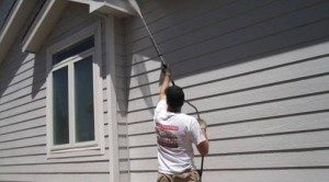 Vivax Pro worker pressure washing siding of house