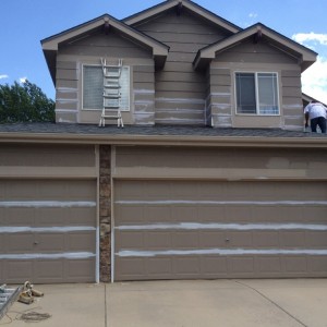 Painter taping off garage doors for new paint